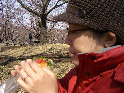 桜を見ながらパンを食べる妻